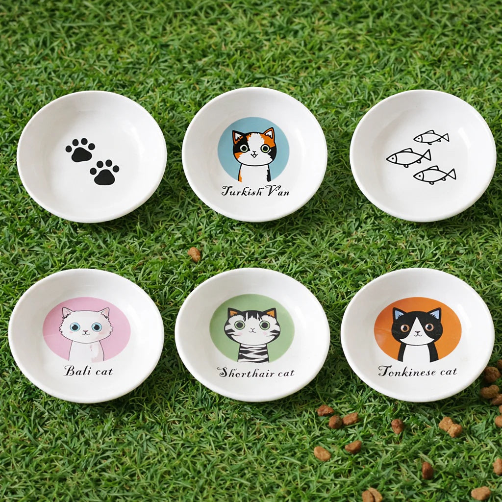 Set of six small white bowls with cat-themed illustrations on a grassy background